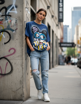 Woman wearing a graphic tshirt and ripped jeans standing against a graffiti covered wall in an urban setting