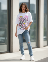 Woman wearing a white tshirt with a graphic design and light blue jeans standing outside a building