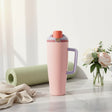 Blush pink insulated travel tumbler with a coral flip cap on a marble counter