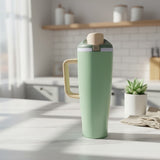 Sage green insulated tumbler with a cream flip cap in a bright kitchen