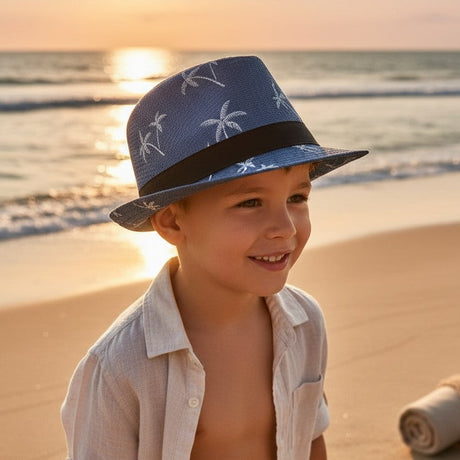 Young boy in a navy straw fedora sun hat with a white palm tree print and black band