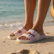 Pink and yellow tie dye double buckle slides worn at the shoreline