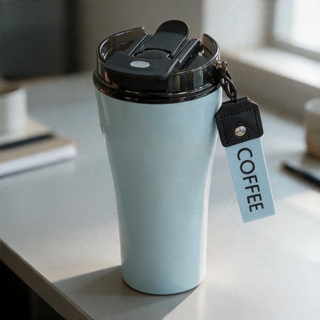 Light blue glossy tumbler with an open black flip lid and a blue COFFEE strap with a leather tab