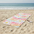 Colorful floral towel on a sandy beach with ocean in the background