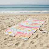 Colorful floral towel on a sandy beach with ocean in the background