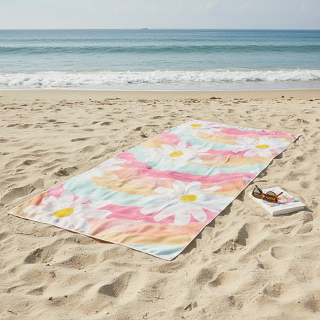 Colorful floral towel on a sandy beach with ocean in the background