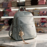 Light blue pebbled backpack with a flower charm tassel on a marble counter in a shop
