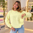 Woman in a pastel yellow crew neck sweatshirt holding its matching mini crossbody pouch