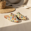 Colorful patterned handmade slippers on a textured surface with a woven basket in the background