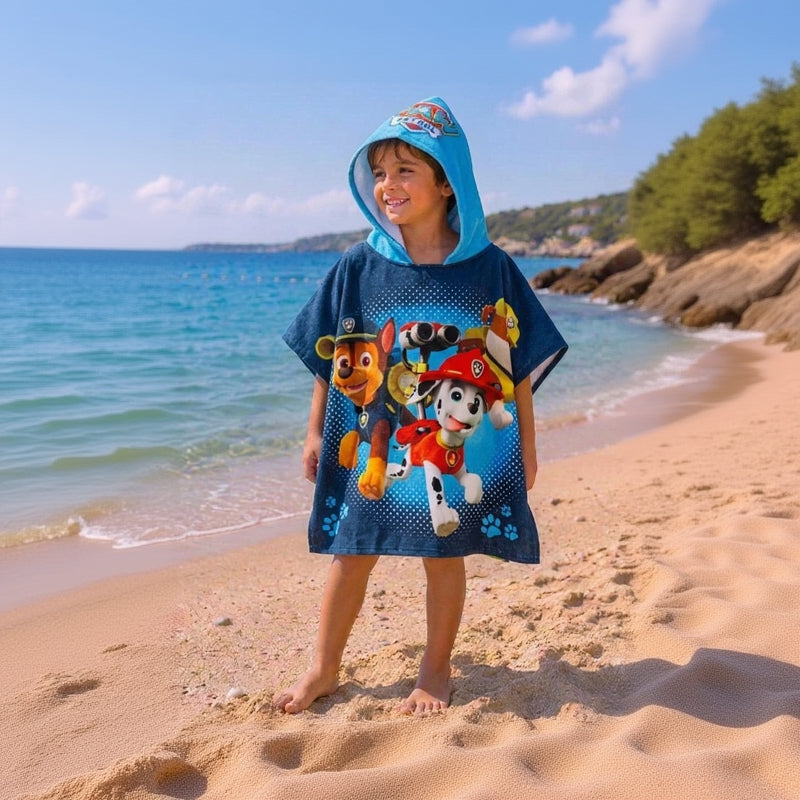 Kid wearing a paw patrol poncho standing on the beach