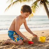 Child wearing Paw Patrol swim shorts playing in the sand
