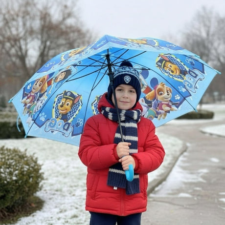 Boy in a red coat holding an open light blue Paw Patrol kids umbrella with Chase and Skye