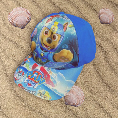 Blue underwater rescue pup cap resting on rippled sand beside pink seashells