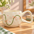 Green vine tied with peach bows winding around a cream mug with red berry dots