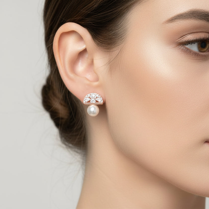 Close-up of a woman wearing a pearl and diamond earring against a neutral background