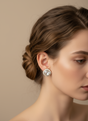 Close-up of a woman wearing a decorative pearl drop earring with a beige background