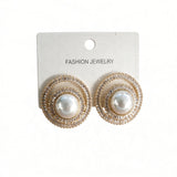 Gold pearl stud earrings circled by spiralling clear crystals on a white card