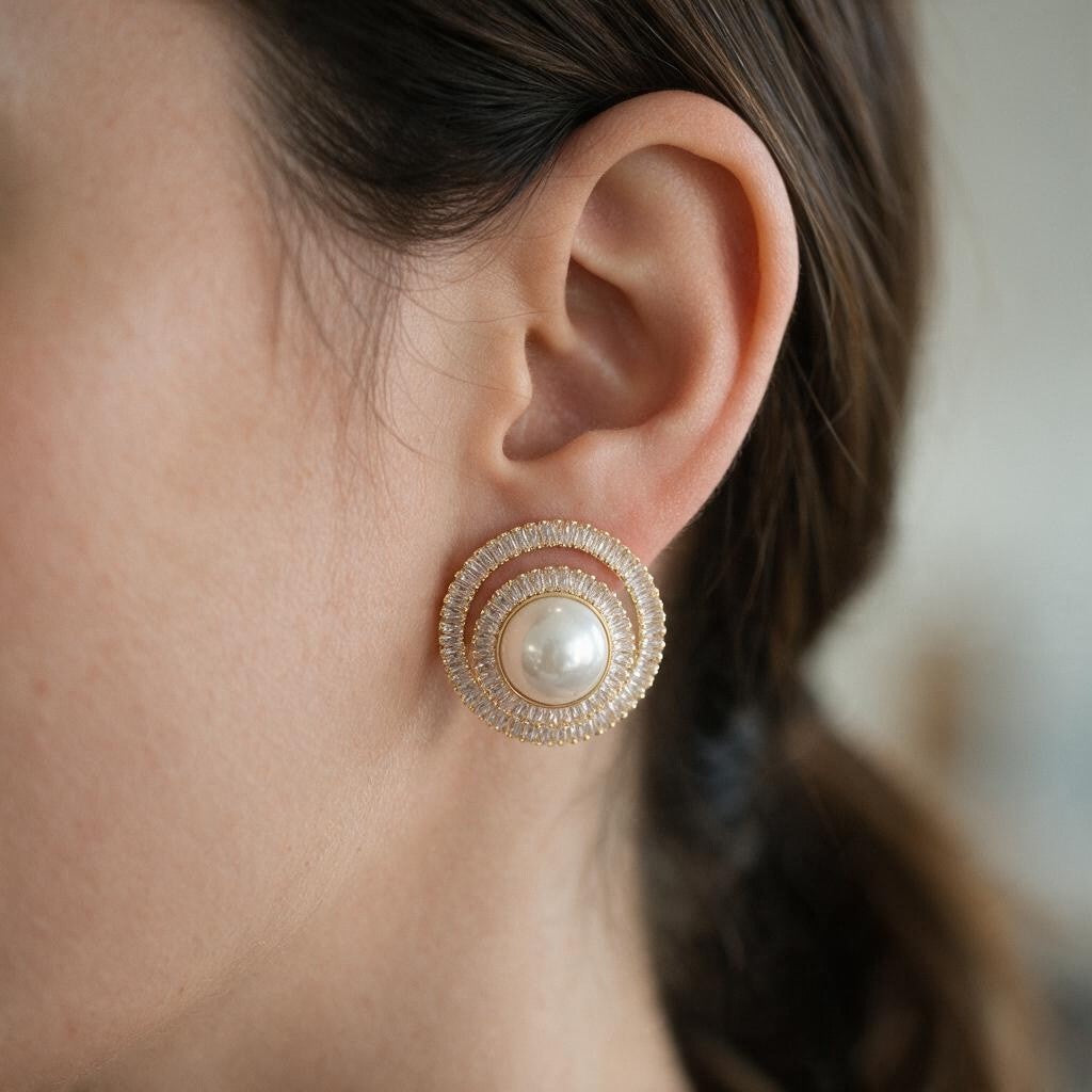 Gold tone pearl stud wrapped in swirling crystal rings worn by a woman with a ponytail
