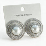 Pair of silver tone pearl spiral earrings with baguette crystals on a white display card