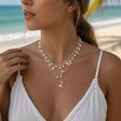 Pearl layered necklace with gold starfish and shell drop, beach jewelry worn by a woman on a blurred background