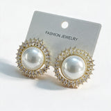 Gold pearl stud earrings ringed with clear crystal points on a white card