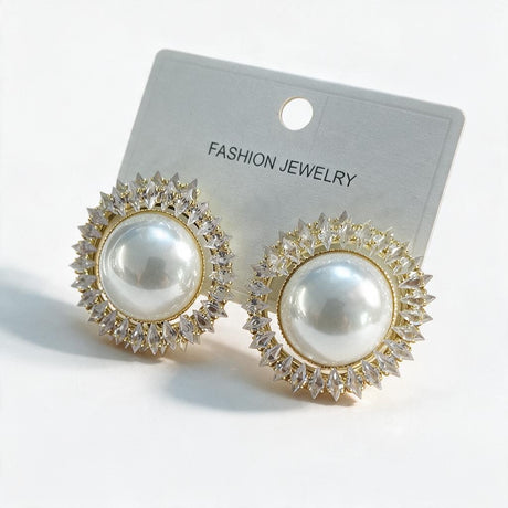 Gold pearl stud earrings ringed with clear crystal points on a white card