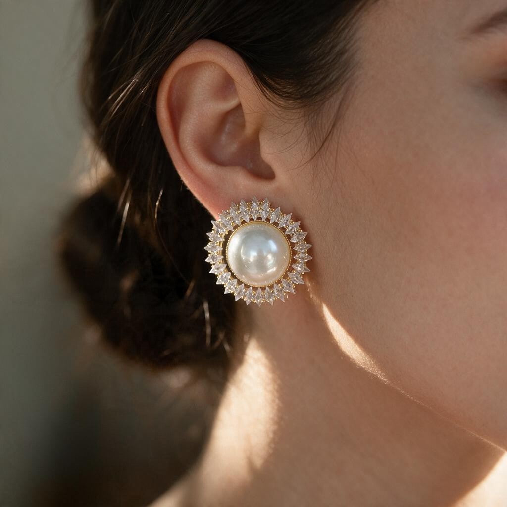 Woman with a low bun wearing a gold tone pearl stud framed by spiky clear crystals