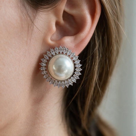 Silver sunburst stud earring with a large white pearl and marquise crystal halo worn on the ear