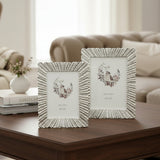 The same fluted frame design in antiqued ivory, standing on a dark walnut surface