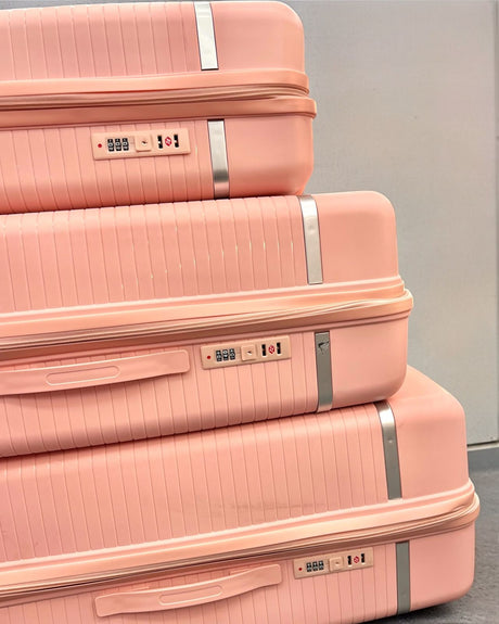Close view of three stacked pink suitcases showing combination locks and zips