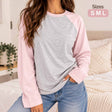Woman in a heather grey long sleeve top with light pink raglan sleeves and jeans