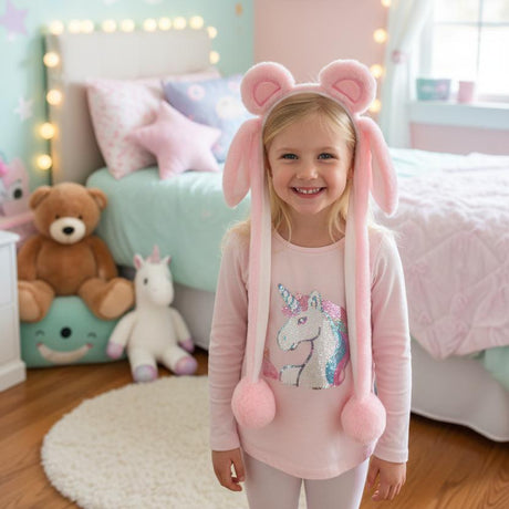 Child in a soft pink bunny ear headband with long hanging ears and fluffy pink pom poms