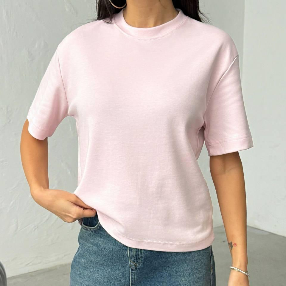 Person wearing a pink tshirt and blue jeans against a neutral background