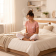 Woman on a bed in a rose bear print pyjama top with pink striped cropped trousers