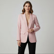 Woman wearing a pink blazer against a plain background