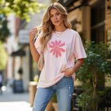 Three tshirts with pink floral designs worn outdoors