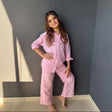Girl in a pink muslin button up shirt and wide leg pants