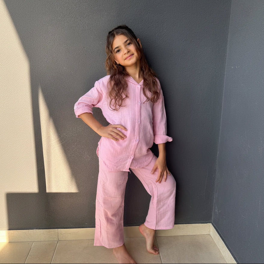 Girl in a pink muslin button up shirt and wide leg pants