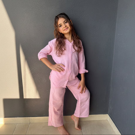 Girl in a pink muslin button up shirt and wide leg pants