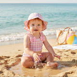 Baby wearing a pink checkered bow swimsuit with a matching bucket hat in the water