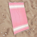Pink and white striped towel on sand
