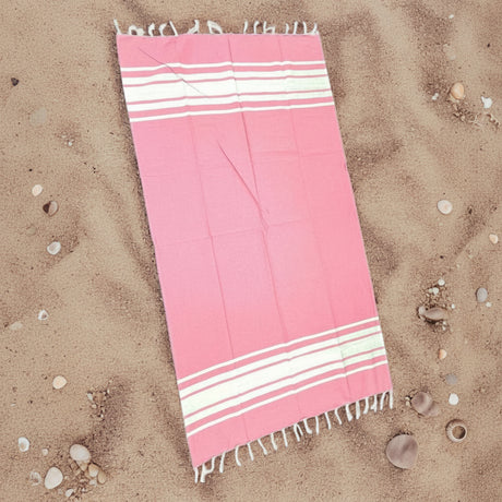 Pink and white striped towel on sand