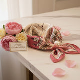 Pink and beige patterned foulard with a pearl on a marble surface with a 'Happy Mother's Day' card