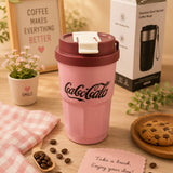 Pink Coca-Cola coffee mug on a wooden table with a box in the background
