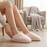 Pale pink plush slip on slippers with white cushioned sole and closed toe