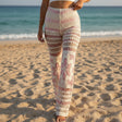 Person wearing patterned leggings on a sandy beach with ocean in the background