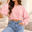Woman in a pink cropped crew neck sweatshirt with balloon sleeves and high waisted jeans