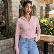 Woman in a soft pink cropped zip hoodie with long thumbhole sleeves at a cafe terrace