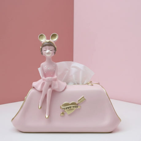 Pink clutch shaped tissue box with a gold heart badge and a girl figurine blowing a bubble