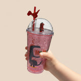 Pink dino glitter cup held in a child's hand showing the red dome figurine